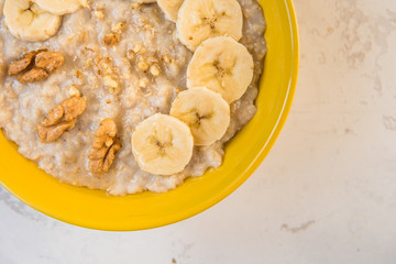Oatmeal with banana and honey. Porridge in a yellow bowl top view