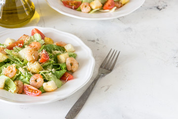 Caesar salad with shrimps on a white background