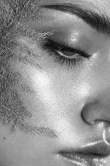 Fototapeta premium Beauty portrait of woman with wet skin and pink branch on her face. Black and white