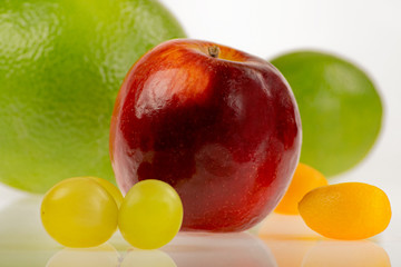 Intensywnie kolorowe i okrągłe - czerwone jabłko z innymi owocami na białym tle - obrazy, fototapety, plakaty