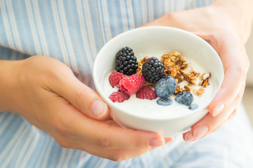 Female holding bowl with yogurt glanola and berries