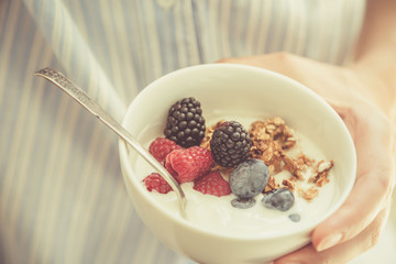 Female holding bowl with yogurt glanola and berries