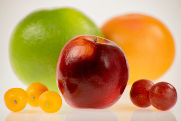Intensywnie kolorowe i okrągłe - czerwone jabłko z innymi owocami na białym tle - obrazy, fototapety, plakaty