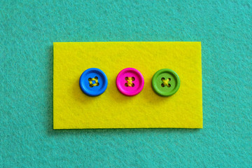 Different ways to sew buttons to felt. Felt piece with bright buttons isolated on felt background....