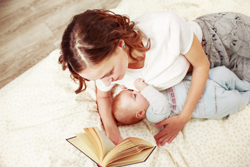 Woman reading a book while brestfeeding a baby on bed