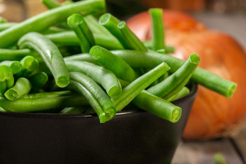 Raw green beans in a black dish