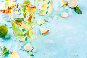 Tropical drink,  Pineapple mojito or lemonade with fresh lime and mint  light blue background, copy space