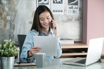 Young asian businesswoman working and talking phone at office table, business casual lifestyle