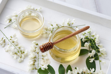White wooden tray with sweet honey jar and spring acacia blossoms, top view