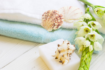 Obraz na płótnie Canvas Natural Sea Spa and aromatherapy concept with blue and white towels, hand made soap, sea shells and fresh white flowers on a white wooden background