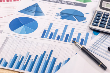 Financial development - calculator and pen on chart and graph paper.
