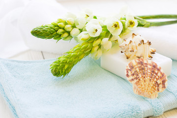 Obraz na płótnie Canvas Aromatherapy Spa Concept on white wooden background with a pile of terry towels, a bar of homemade soap, sea shell and white flowers