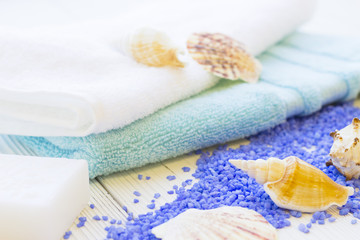 Fototapeta na wymiar Spa Treatment Concept mock up with natural lavender bath salt, terry towels, a bar of hand made soap and sea shells on a white wooden table