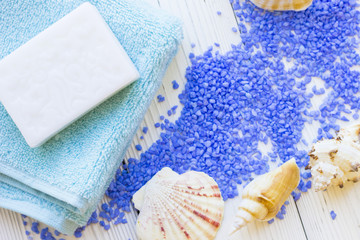 Spa Treatment Concept mock up with natural lavender bath salt, terry towels, a bar of hand made soap and sea shells on a white wooden table , top view