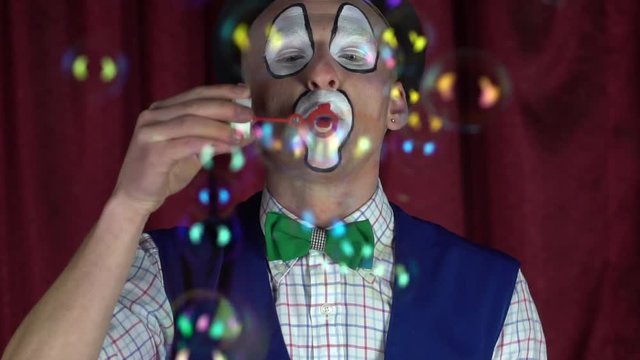 The clown blows soap bubbles