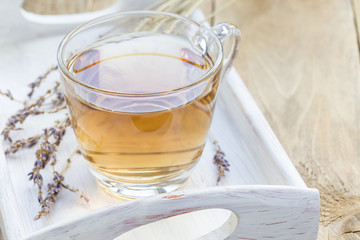 Healthy herbal lavender tea in glass cup with lavender flowers on background, horizontal