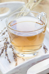 Healthy herbal lavender tea in glass cup with lavender flowers on background, vertical