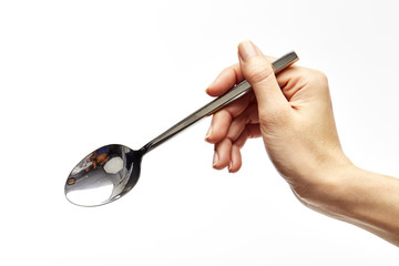 woman's right hand holds a spoon - obrazy, fototapety, plakaty