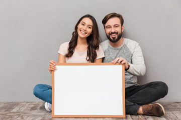 Portrait of a happy young couple holding blank board