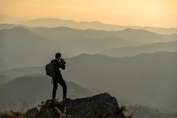 Photographer with camera in hand on top of mountain.