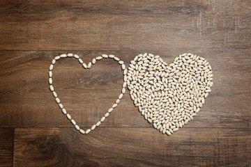 Heart of white beans on brown wooden table
