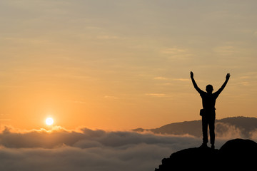 Fototapeta premium Silhouette of man hold up hands on the peak of mountain.