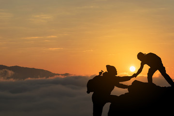 Two friends helping each other and with teamwork trying to reach the top of the mountains
