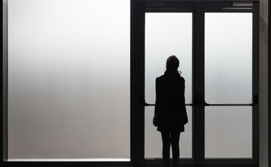 Depressed woman waiting in front a glass door in a white room ready to react - Disease - Abuse -...