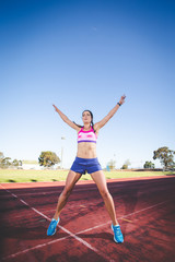 Fototapeta premium Female fitness model and track athlete sprinting on an athletics track made from tartan