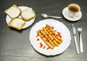 Breakfast - boiled sausages with ketchup, slices with butter and a cup of tea.