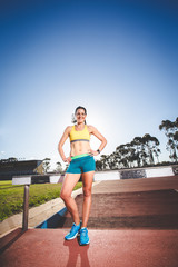 Female fitness model and track athlete sprinting on an athletics track made from tartan