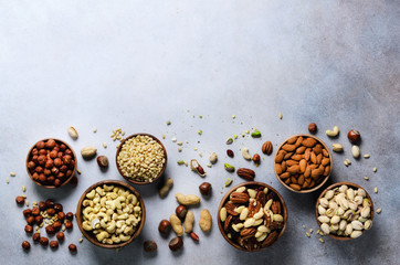 Assortment of nuts in wooden bowls. Cashew, hazelnuts, walnuts, pistachio, pecans, pine nuts,...