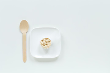 Protein powder in scoop on small plate with spoon