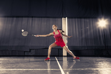 Young woman playing badminton at gym - obrazy, fototapety, plakaty