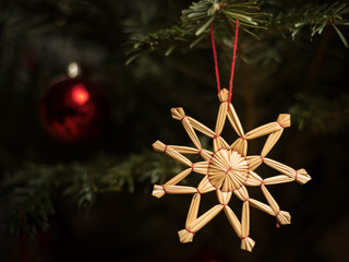 A straw star hanging on a christmas tree
