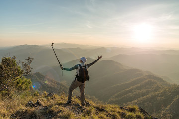 Photographer with action camera in hand on top of mountain.