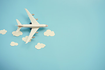 Flat lay design of travel concept with plane and cloud on blue background with copy space. - obrazy, fototapety, plakaty