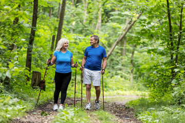 Elderly couple enjoying summer walk in the forest.
