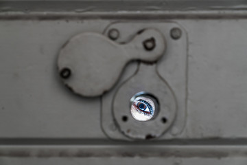 Auge blickt durch Türspion einer Zellentür ins Freie