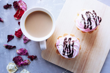 Coffee and pink cakes on the gray background. Flat lay view.