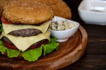 Homemade burger on wooden cutting board.