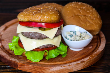 Homemade burger on wooden cutting board.