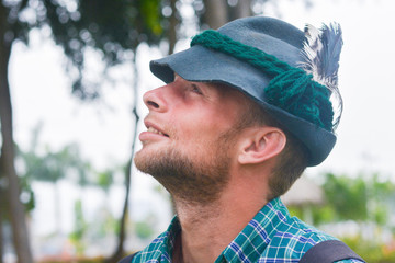 Young caucasian man wearing typical bavarian clothes with hat with fear in the summer park.