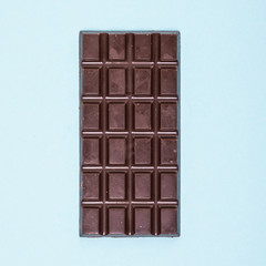 Dark chocolate bar isolated on a blue background