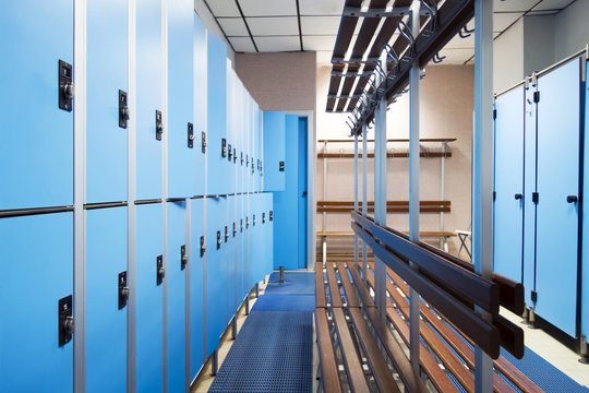 an empty locker room in the sports club, school, section. line lockers with numbers and locks and a shower. in the center a wooden clothes hanger and a dressing-gown