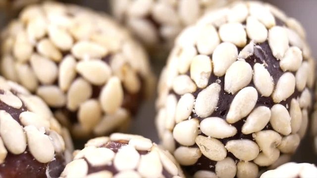Heap of chocolate balls candies in sugar glaze isolated on white background. Candy peanuts with sesame seeds