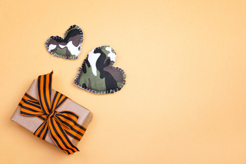 Gift box with st george ribbons with khaki hearts on the yellow background.