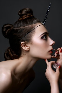 angivet Hilse Encommium Close-up portrait of a beautiful young girl, in the image of a black  unicorn, applying make-up by make-up artist. Process of making makeup.  Stock Photo | Adobe Stock