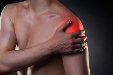 Man with pain in shoulder on black background