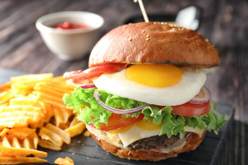 Tasty burger with fried egg on table, closeup
